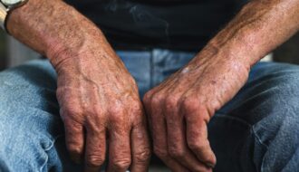 Elderly man's hands resting with a cigarette, representing anticipatory grief and watching someone you love decline