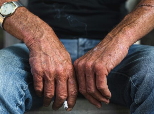 Elderly man's hands resting with a cigarette, representing anticipatory grief and watching someone you love decline