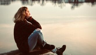 woman sitting alone on dock reflecting anticipatory grief