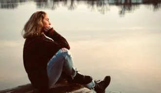 woman sitting alone on dock reflecting anticipatory grief