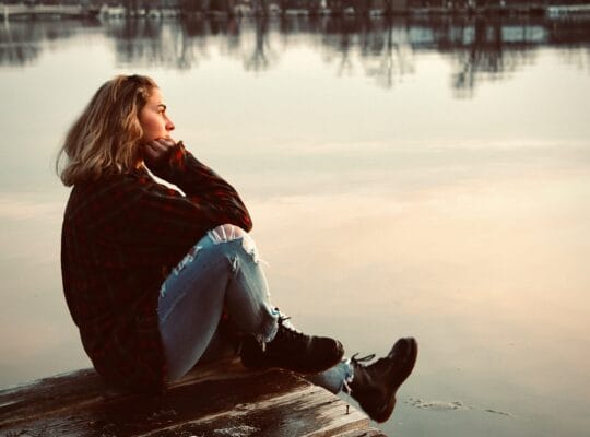 woman sitting alone on dock reflecting anticipatory grief
