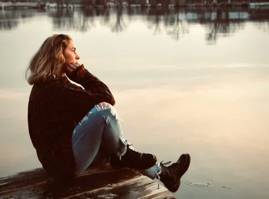 woman sitting alone on dock reflecting anticipatory grief