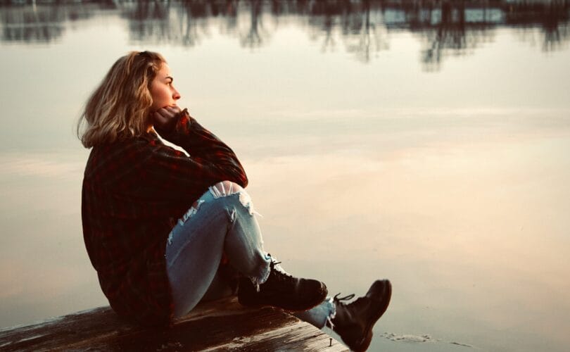 woman sitting alone on dock reflecting anticipatory grief
